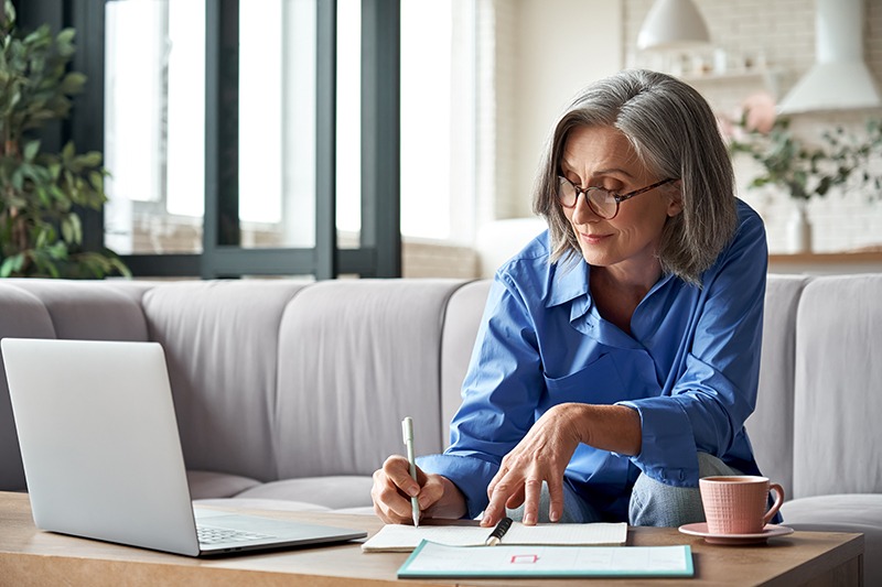 femme retraitée devant son ordinateur remplissant des documents